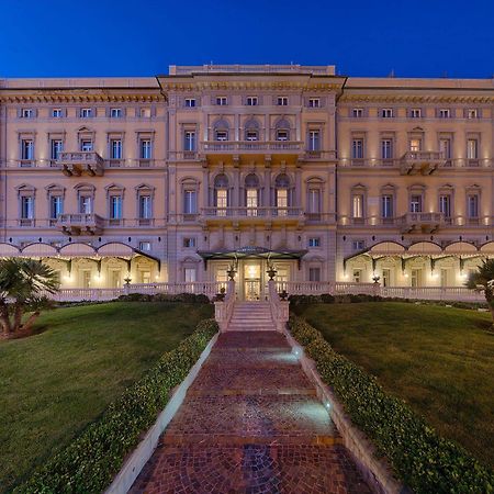Grand Hotel Palazzo Livorno MGallery Collection Esterno foto The photo shows a large, elegant building, likely a hotel or historic structure, illuminated at dusk. It features a classic architectural style with multiple balconies and ornate detailing on the façade. The building is framed by well-maintained gree