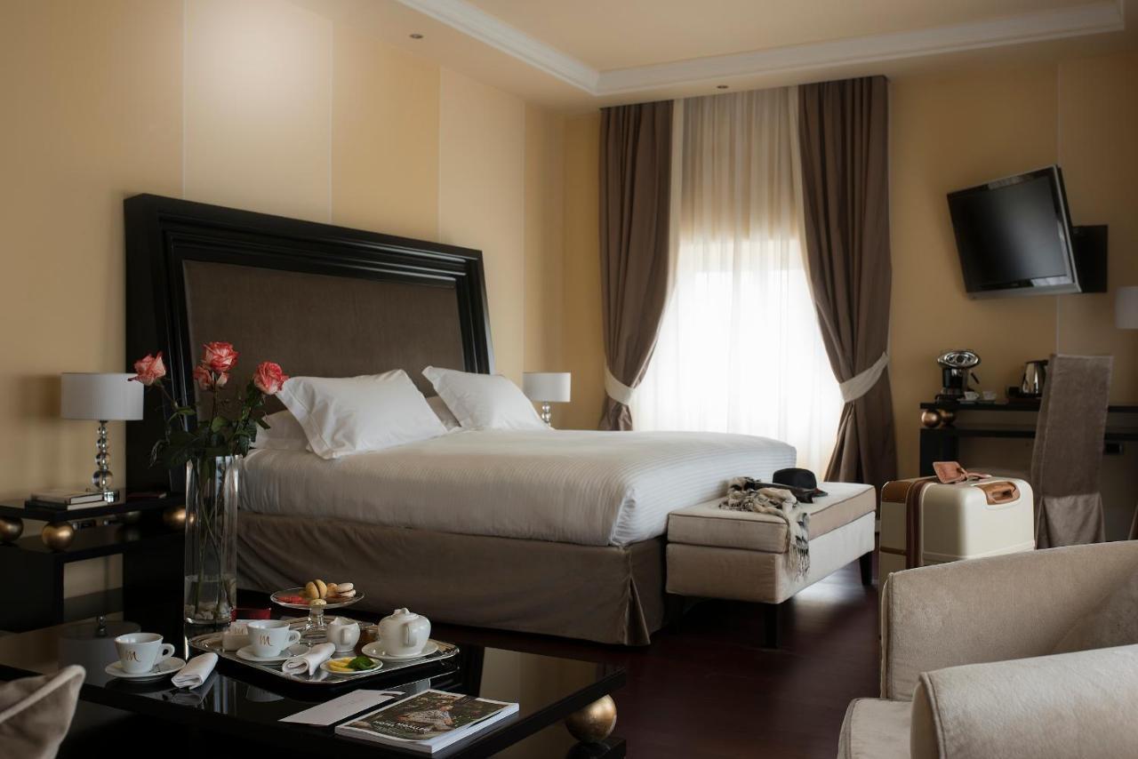 Grand Hotel Palazzo Livorno MGallery Collection Esterno foto The photo shows a luxurious hotel room featuring a large bed with a plush headboard. The room is elegantly decorated with soft colors, including cream and beige tones. Natural light filters in through large windows with sheer curtains, illuminating t