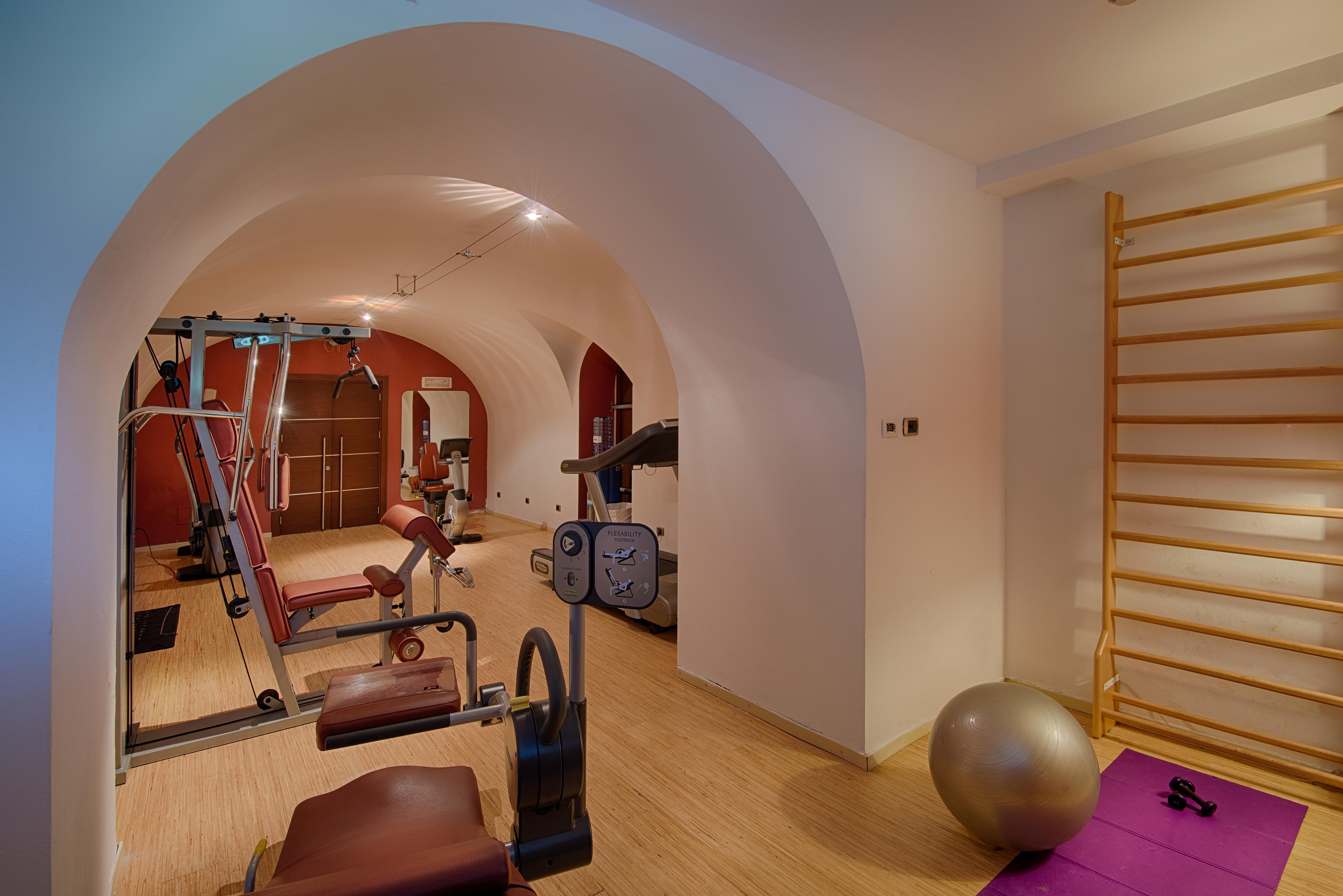 Grand Hotel Palazzo Livorno MGallery Collection Esterno foto The photo shows a home gym or fitness area with a clean, modern design. It features exercise equipment such as a weight machine, a stationary bike, and a variety of workout mats. There is also a large exercise ball and a wooden wall bar for stretchin