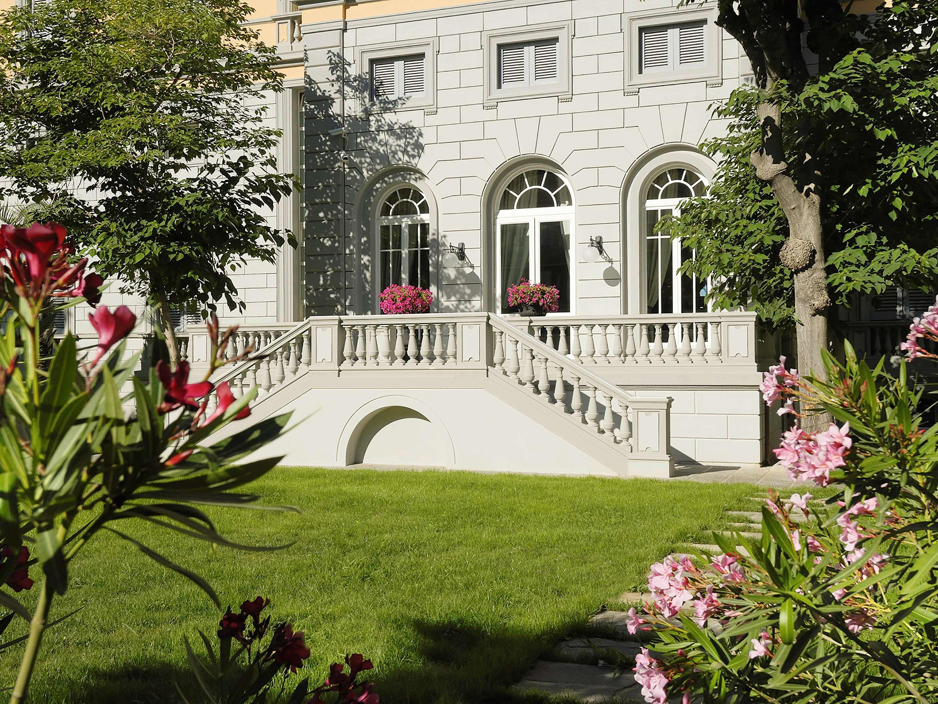 Grand Hotel Palazzo Livorno MGallery Collection Esterno foto The photo shows a beautifully landscaped area featuring a large, elegant building with stone architecture. The building has several large arched windows that allow plenty of light in. A staircase leads up to a terrace with decorative railings. The su