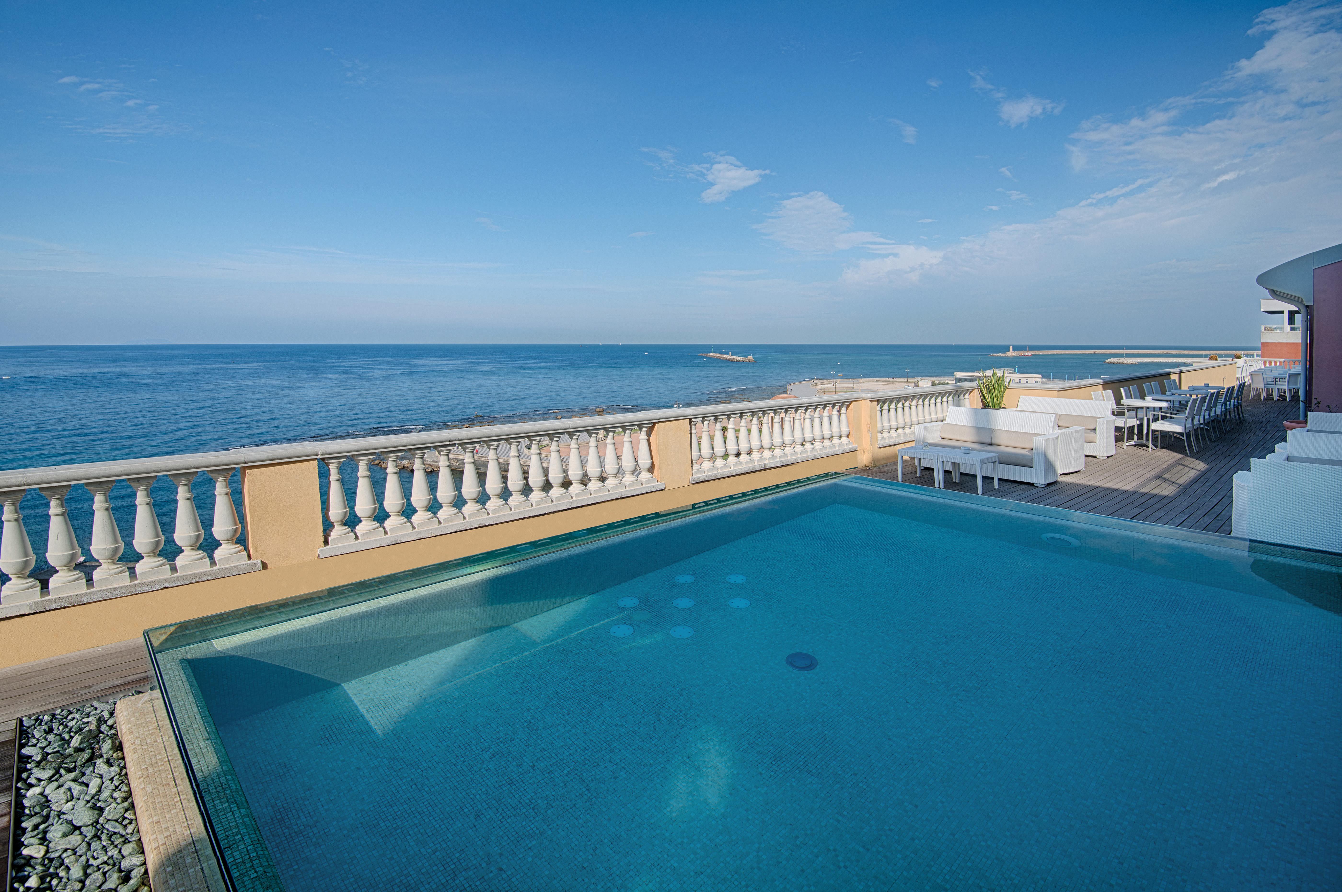Grand Hotel Palazzo Livorno MGallery Collection Esterno foto The photo depicts a serene outdoor setting featuring a swimming pool that appears to be overlooking the ocean. The pool has a clear, inviting surface and is bordered by a sophisticated railing. In the background, the expansive view of the ocean is vi